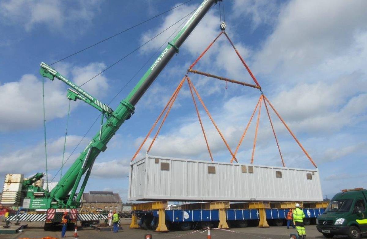 Crane operated by JGC Engineering on the dock moving shipping containers onto a platform